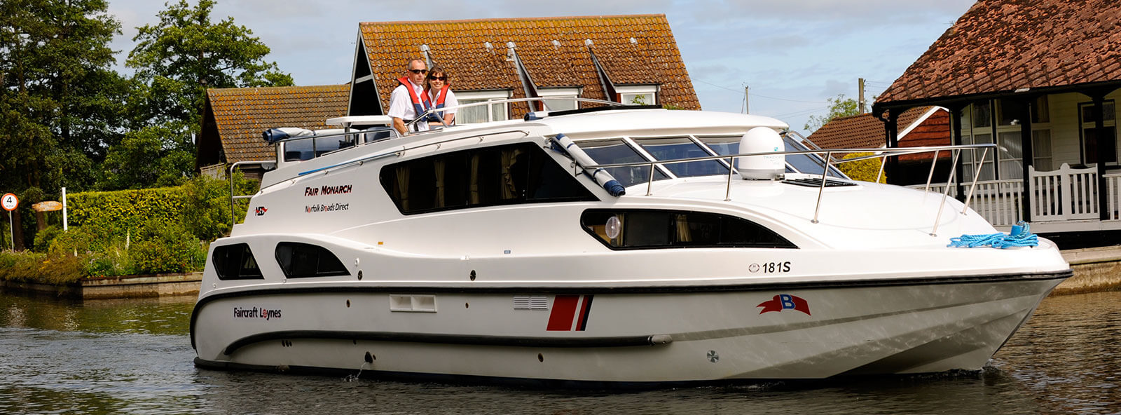 A couple cruising as part of a norfolk broads boat hire