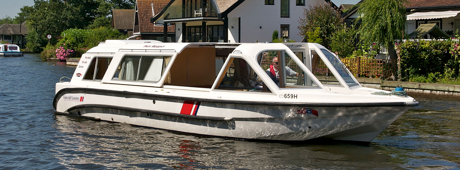 A man cruising along the Norfolk Broads on board a holiday boat